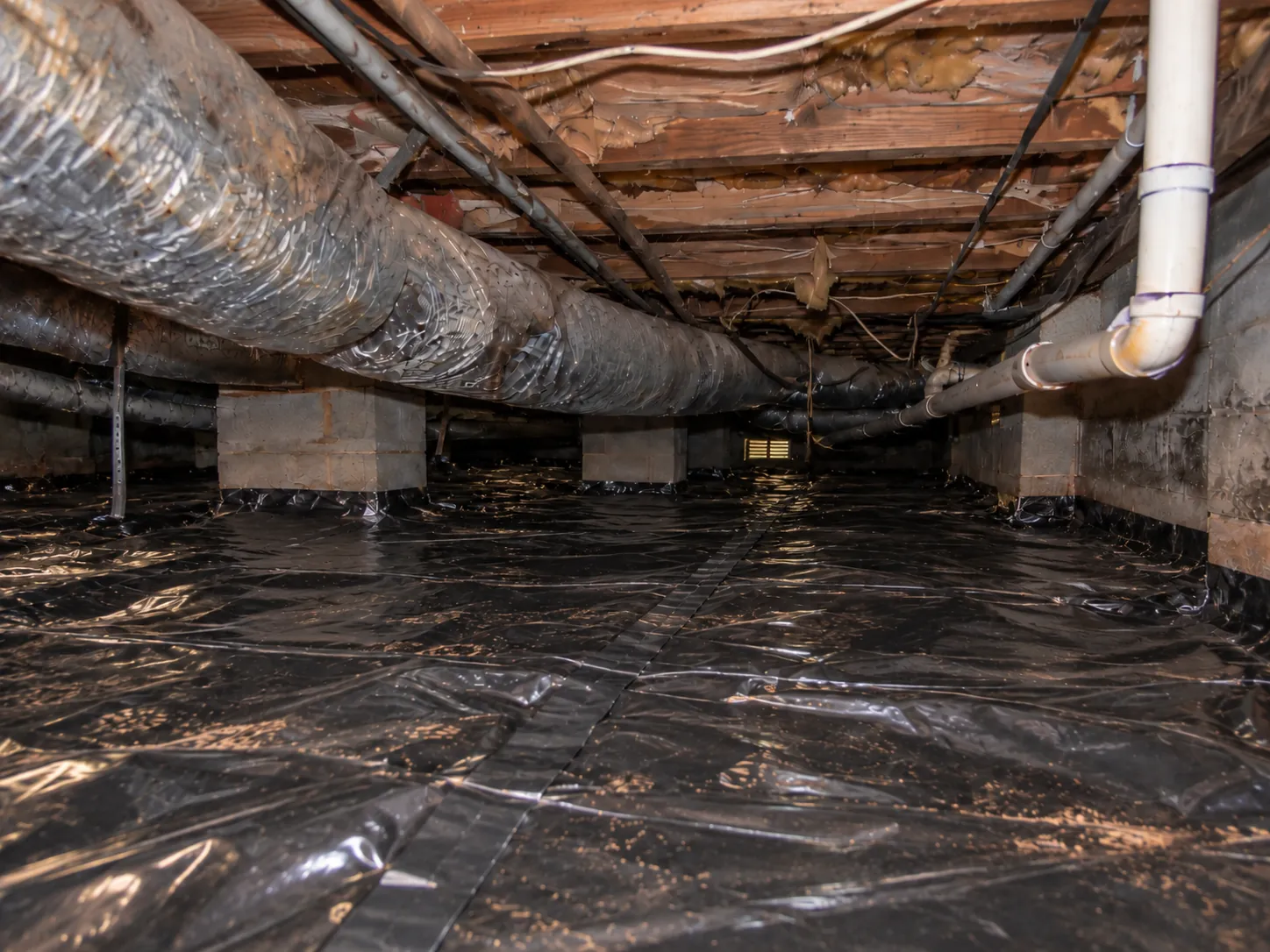 A black ground vapor barrier covering the crawl space floor after installation